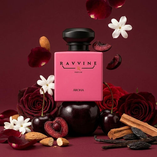 A pink rectangular perfume bottle labeled 'RAVINE FRAGRANCE' and 'ARCHA' stands centered on a dark burgundy background, surrounded by red roses, cherries, white flowers, cinnamon sticks, almonds, and dried fruit pieces. Inspired by Tom ford Lost Cherry